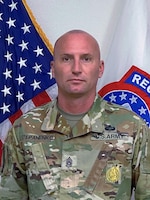 Photo of Command Sgt. Maj.posing for command photo in front of U.S. flag and United States Recruiting Command (USAREC) flag.