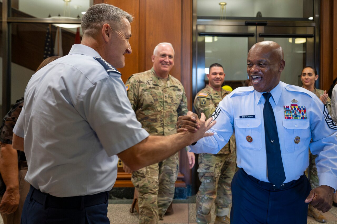 Two service members shake hands.