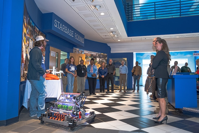 Photo shows people watching demonstration of a robot rolling on the floor