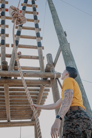 U.S. Marine Corps 1st Lt. Alexandra Arnold, a series commander with Fox Company, 2nd Recruit Training Battalion, guides a recruit down a rope during a confidence course training event at Marine Corps Recruit Depot San Diego, California, Oct. 24, 2024. The confidence course challenges recruits physically and mentally through obstacles that require confidence in their strength, balance, and determination. (U.S. Marine Corps photo by Cpl. Sarah M. Grawcock)