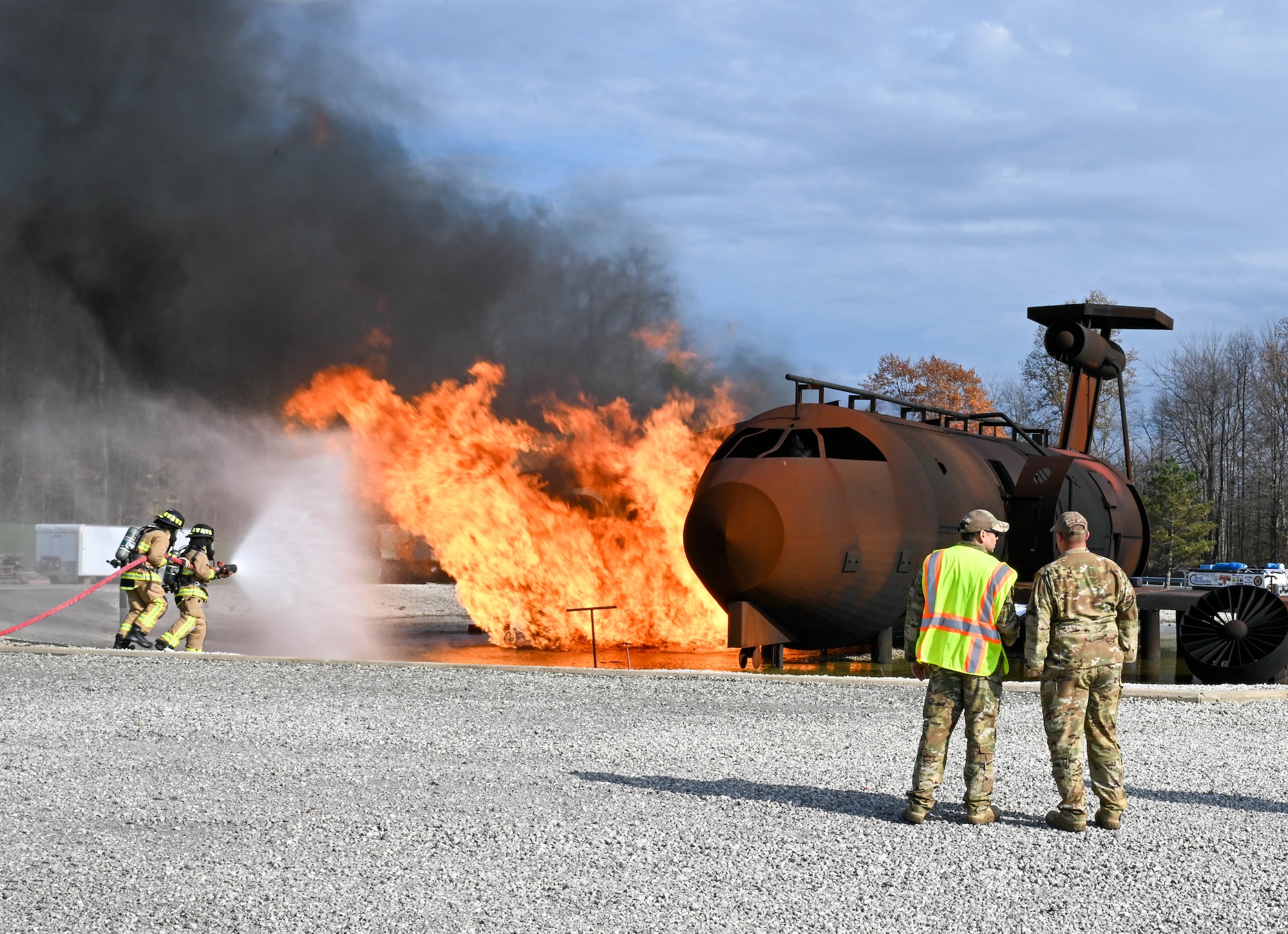 Firefighters assigned to the 910th Civil Engineer Squadron fight a simulated aircraft fire, Nov. 4, 2024, while wing inspection team members watch during Combat Readiness Exercise Buckeye II at Youngstown Air Reserve Station, Ohio.