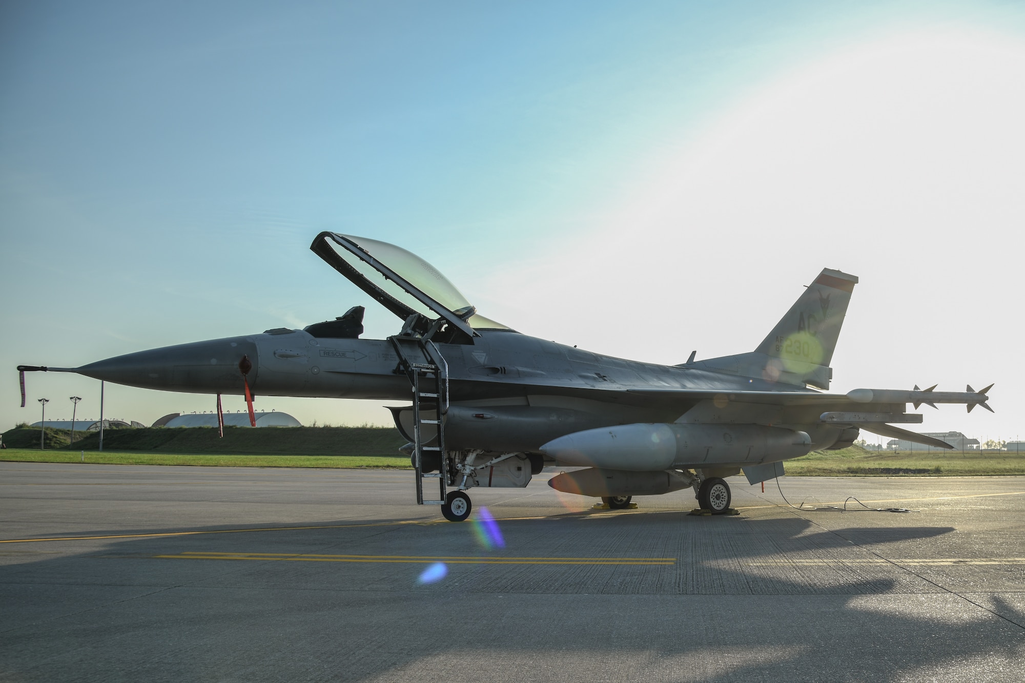 An F-16C sits on display on a flightline during the sunrise.