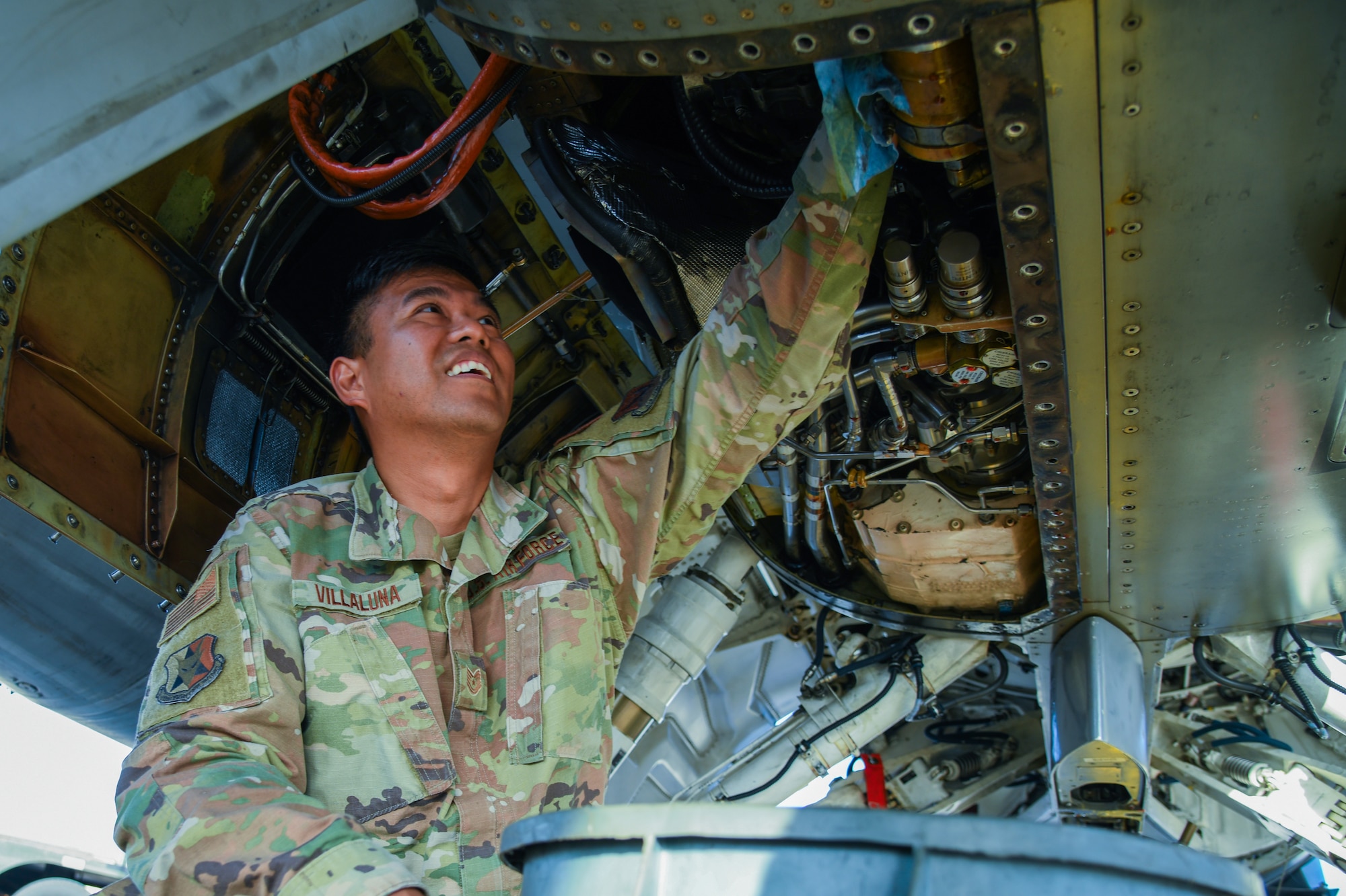 An aircraft maintainer reaches up into a F-16C fighter jet.