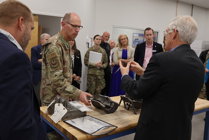 Photo shows group of people looking at parts on table