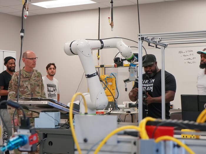 Photo shows people watching a man input information into a machine