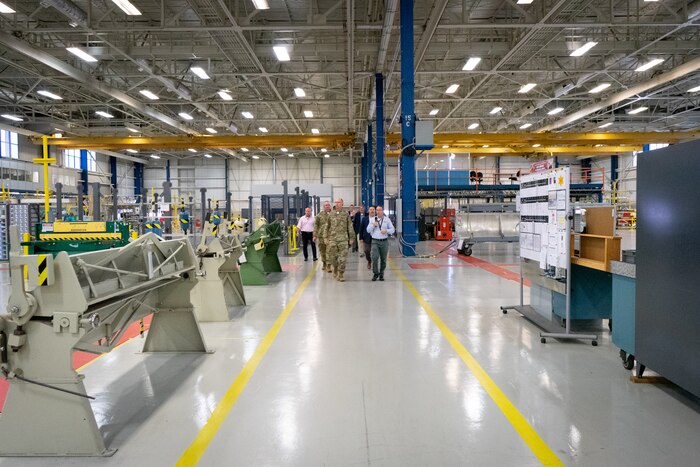 Photo shows group of people walking along lines of machines