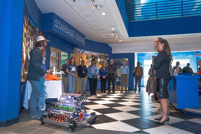Photo shows people watching demonstration of a robot rolling on the floor