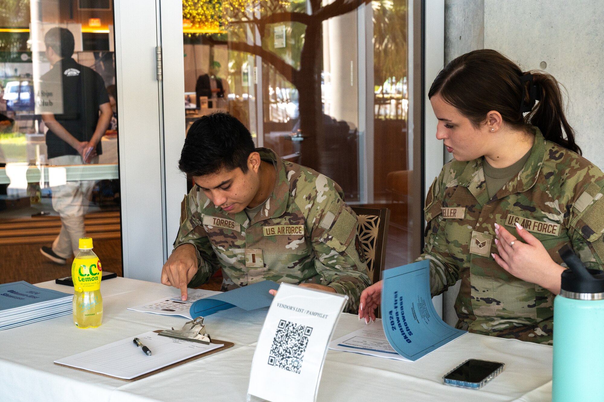 two military members are sitting on the desk, checking participants in.