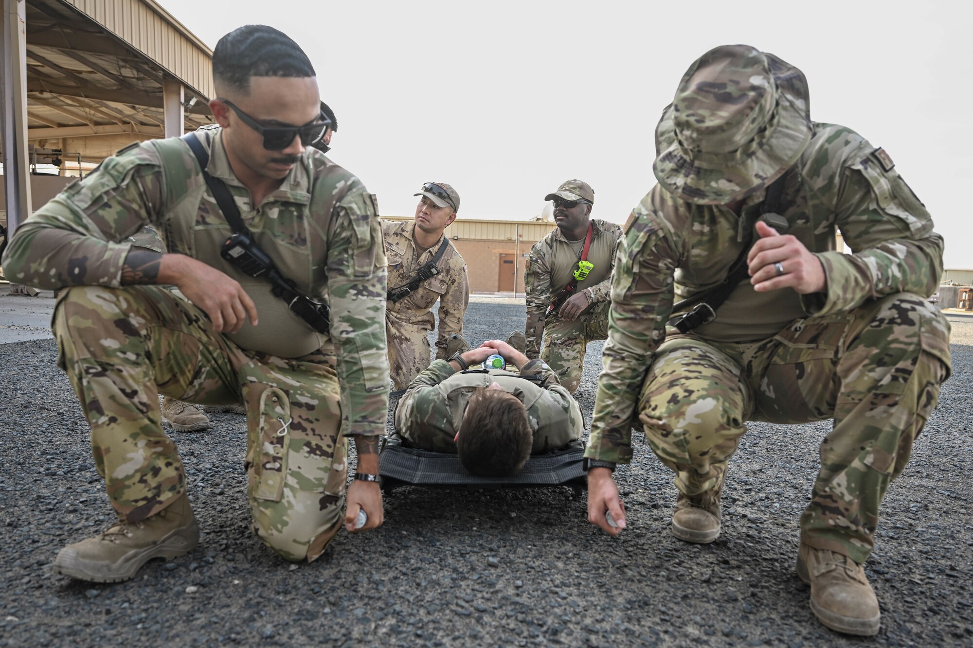 Men in uniform prepare to lift a litter patient off the ground.