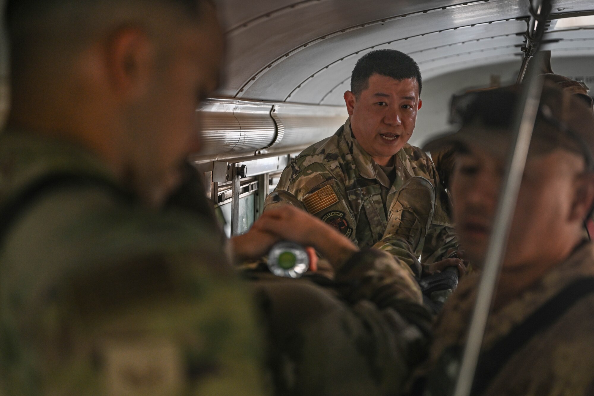 A man in uniform instructs other men in uniform while on an ambulance bus.