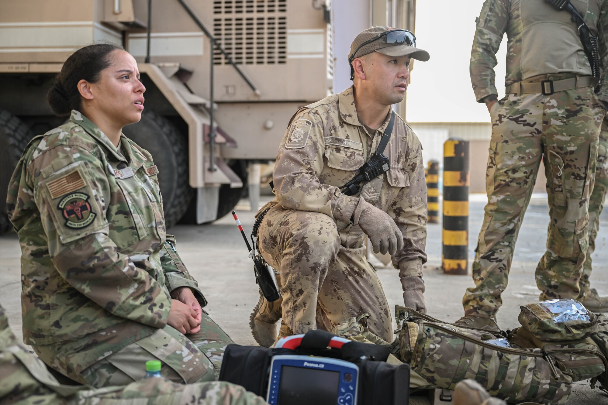 A man and woman in uniform kneel on the ground.