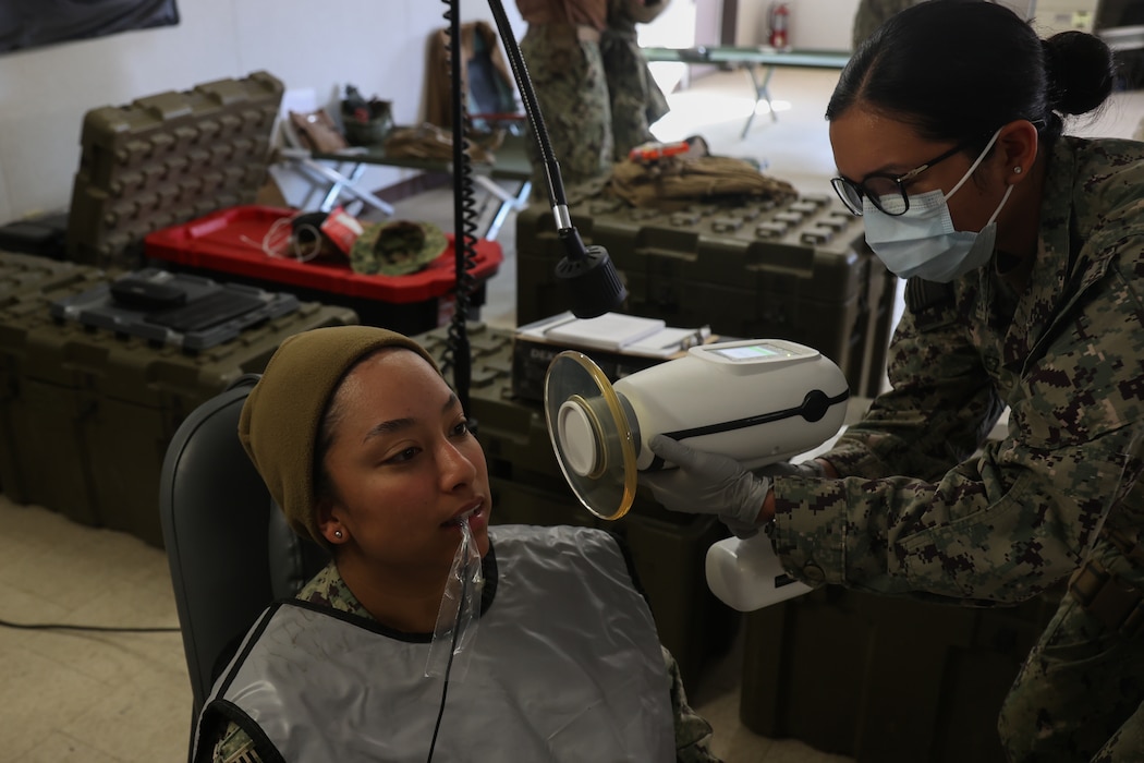 241029-N-BR551-1462 Hospital Corpsman 3rd Class Sylvia Peralez conductas a dental check-up on Utilitiesman 2nd Class Joane Duran during a field trainign exercise at Ft. Hunter Liggett on October 29th, 2024. NMCB 4 is implementing a robust construction skill training plan to prepare for a dynamic mission set throughout the Indo-Pacific in support of Combatant Commander strategic objectives. (U.S. Navy Photo by Mass Communication Specialist 1st Class Dakota Rayburn)