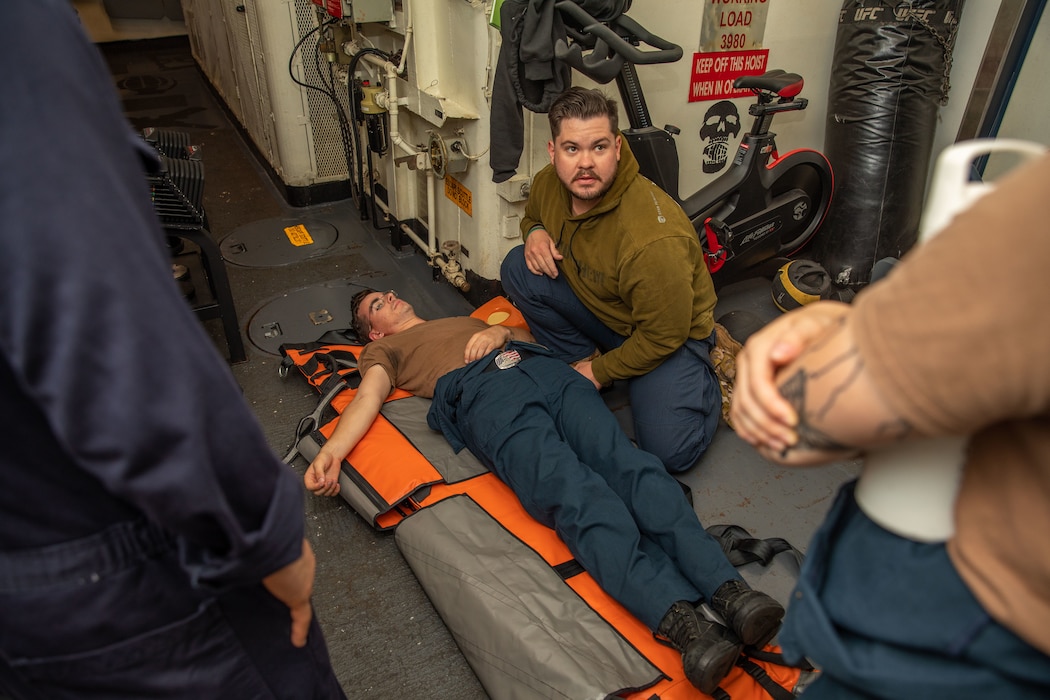 240813-N-AY869-1024 U.S. CENTRAL COMMAND AREA OF RESPONSIBILITY (Aug. 13, 2024) A U.S. Navy Hospital Corpsman demonstrates bearer techniques during advanced first aid training aboard the Arleigh Burke-class guided-missile destroyer USS Cole (DDG 67). (Official U.S. Navy photo)