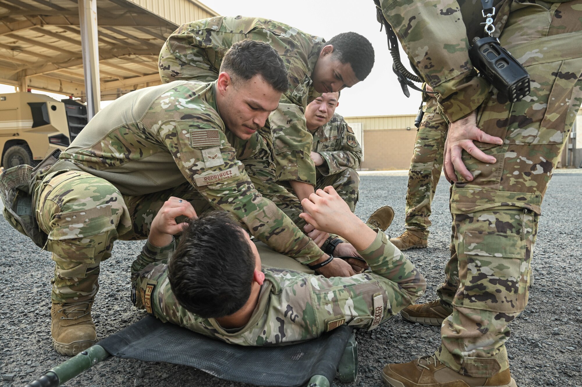 Men in uniform practice strapping another man in uniform onto a litter.