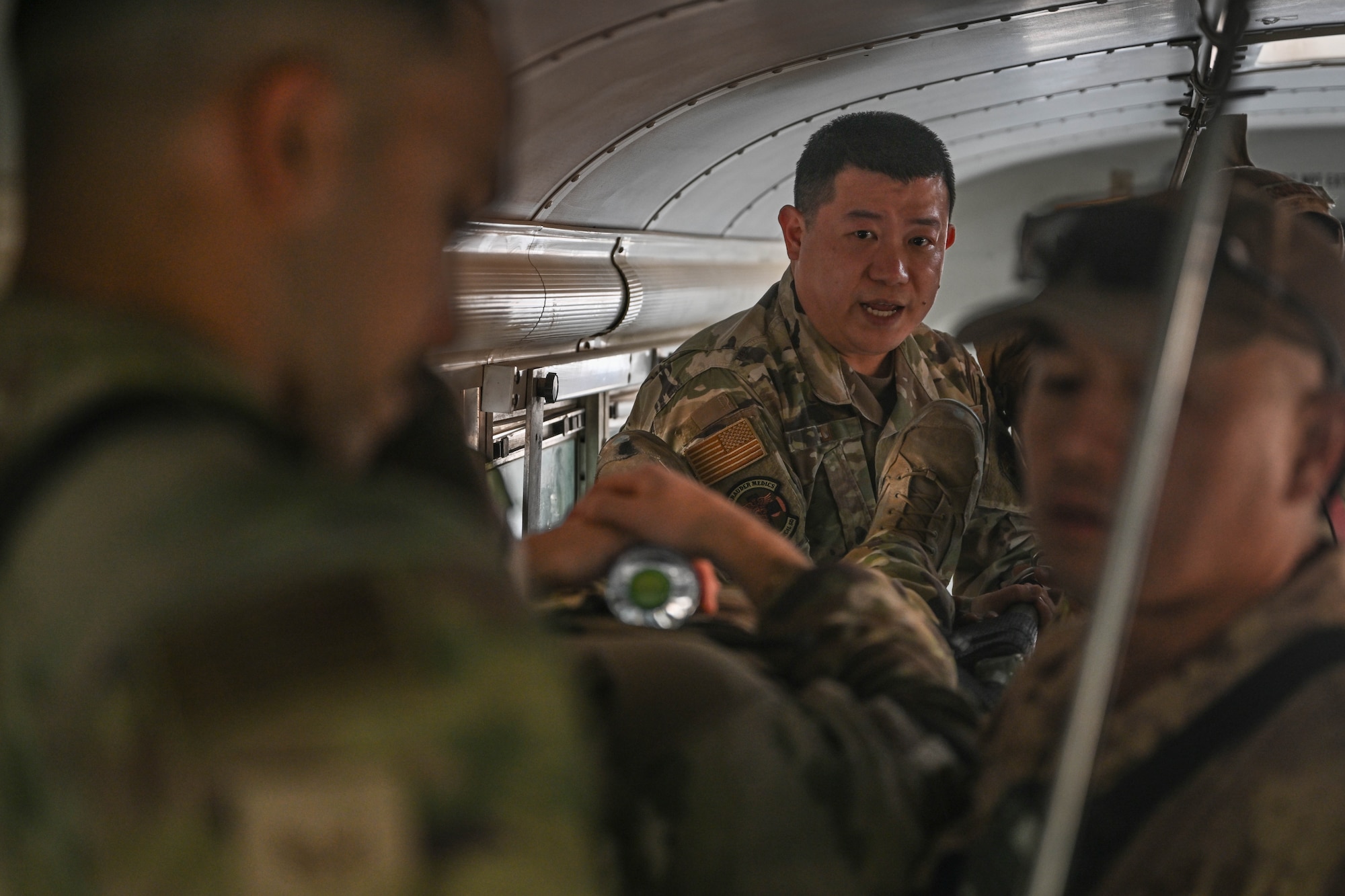 A man in uniform instructs other men in uniform while on an ambulance bus.