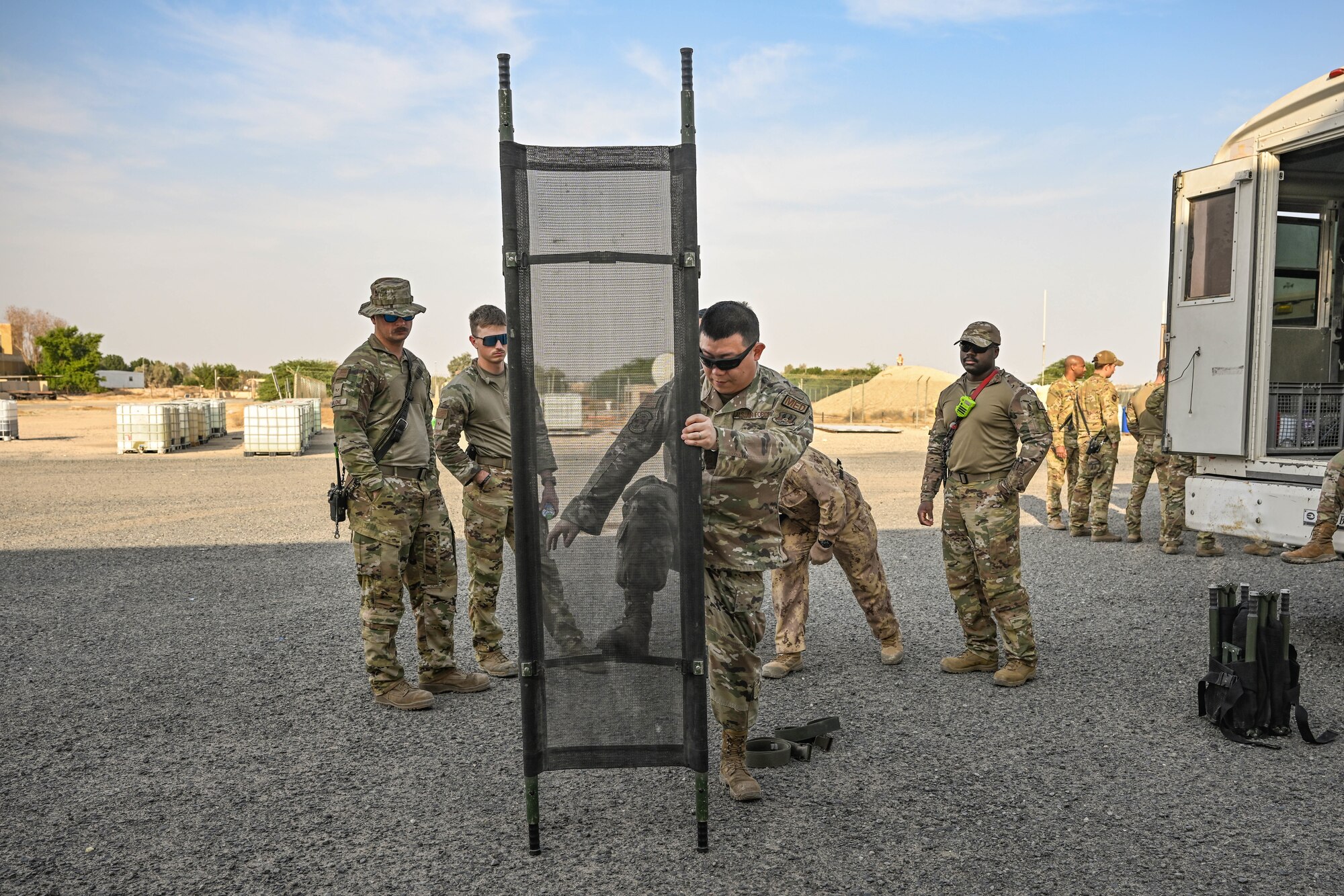 A man in uniform opens a litter in front of other men in uniform.