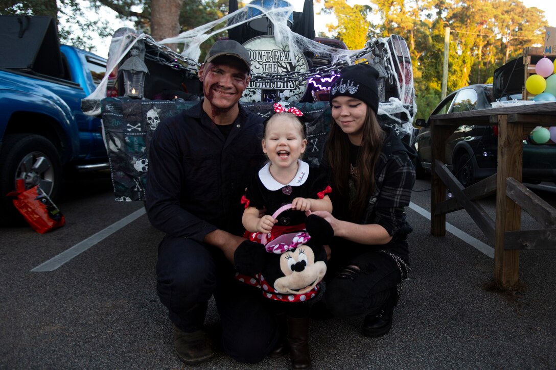 U.S. Marine Corps Sgt. Daniel Briggs, motor transport mechanic, with Headquarters and Service Company, II Marine Expeditionary Force Support Battalion (II MSB), II Marine Expeditionary Force, poses with his family for a photograph in front of their decorated vehicle during a II MSB Trunk or Treat event at Marine Corps Base Camp Lejeune, North Carolina, Oct. 25, 2024. II MSB Marines, sailors and civilians volunteered for and participated in this annual event, building unit cohesion, camaraderie, social fitness and individual Marines’ resiliency, as well as increasing family readiness within this high operations tempo unit. (U.S. Marine Corps photo by Cpl. Tyler M. Raab)