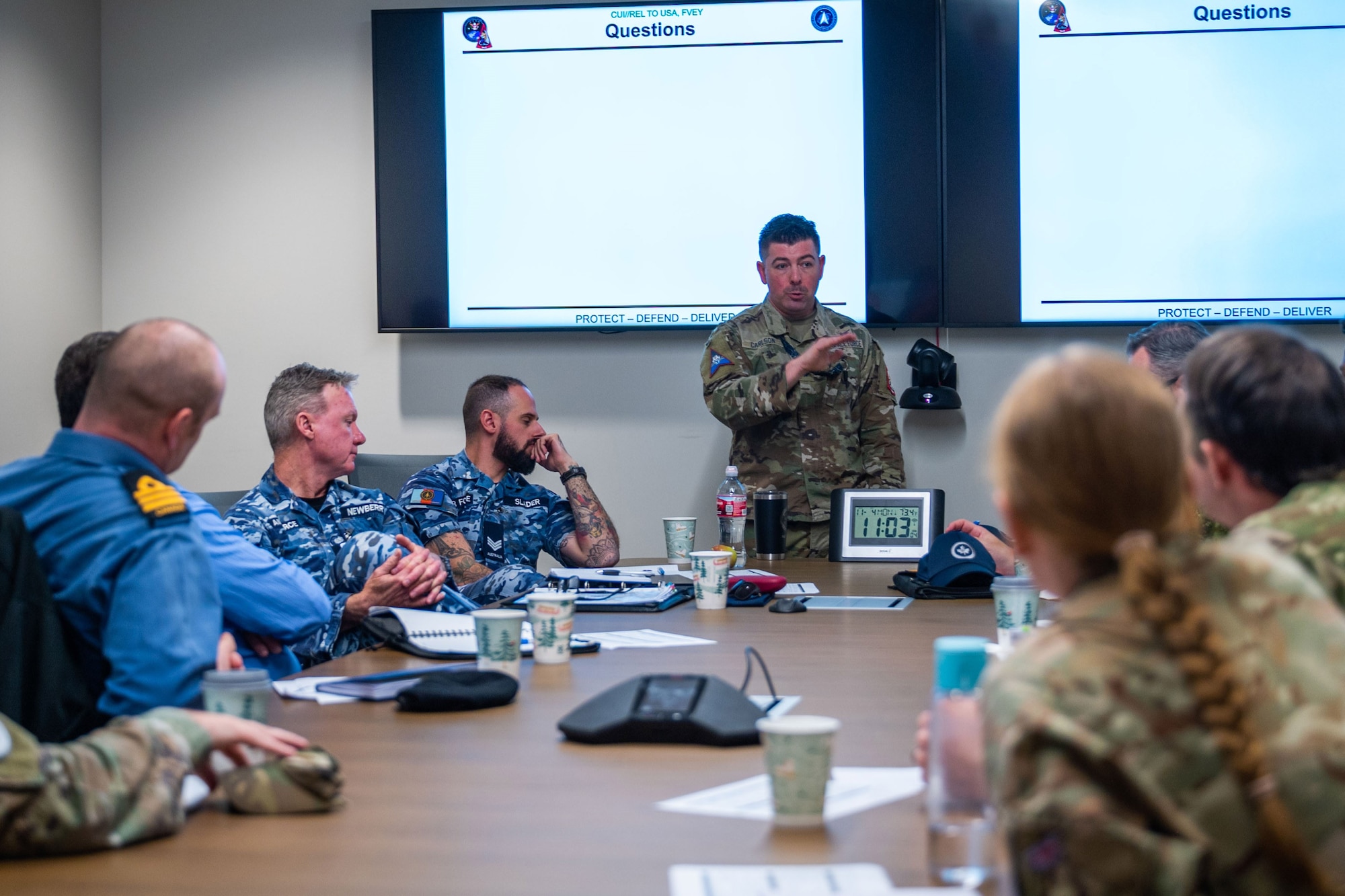Military members engage in discussion around a conference table.