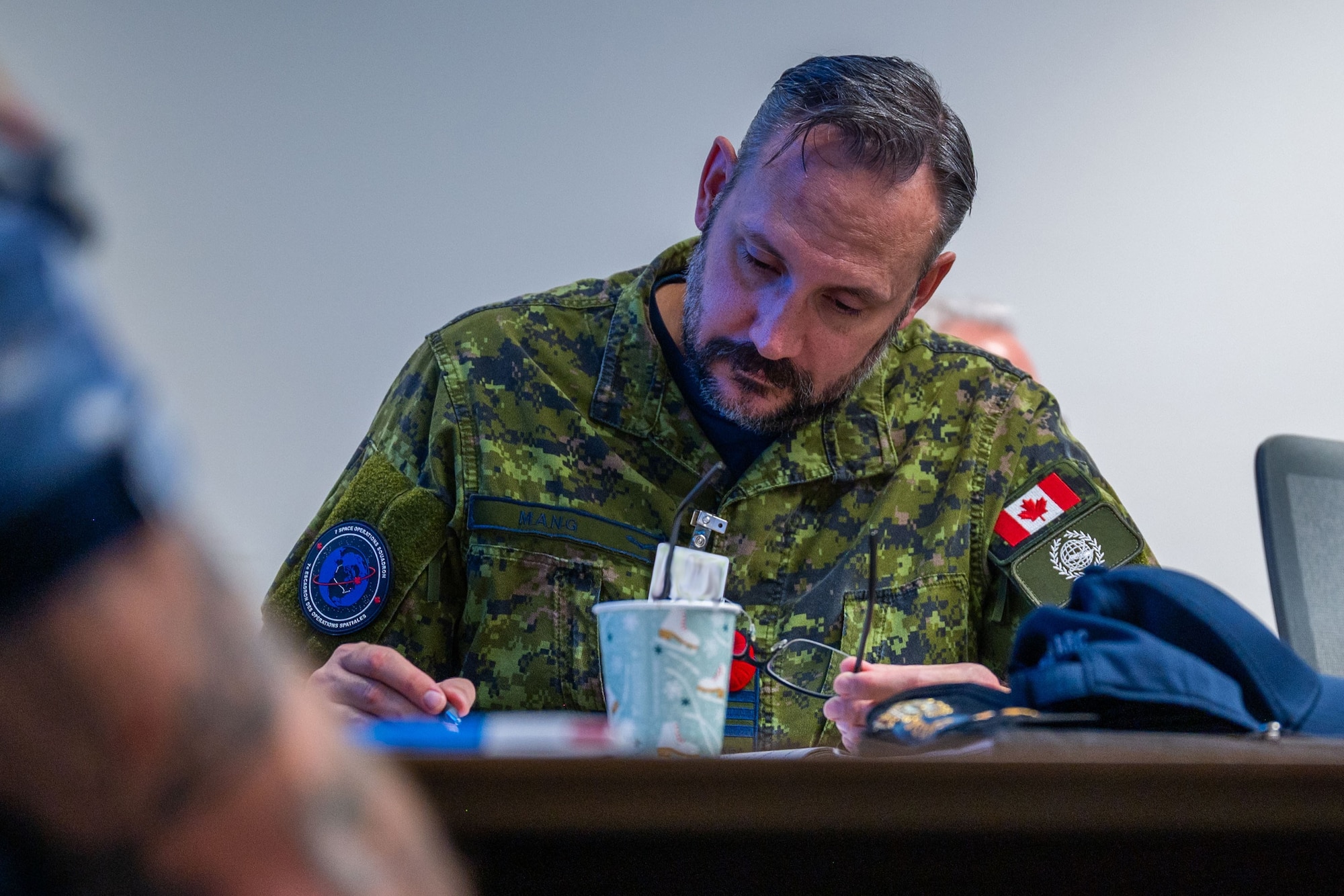 A military member takes notes sitting at a conference table.