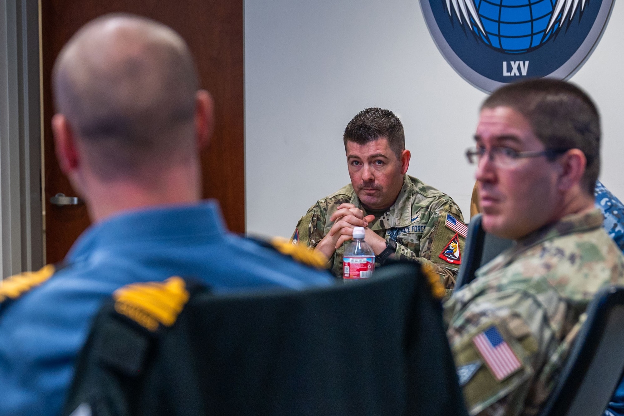 Military members engage in discussion at a conference table.