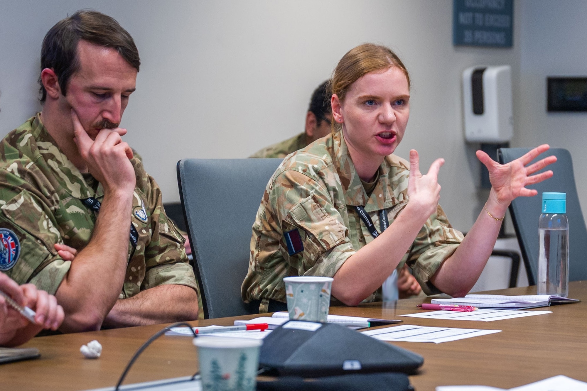 Two military members discuss at a conference table.