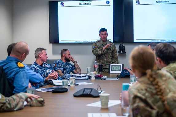 Military members engage in discussion around a conference table.