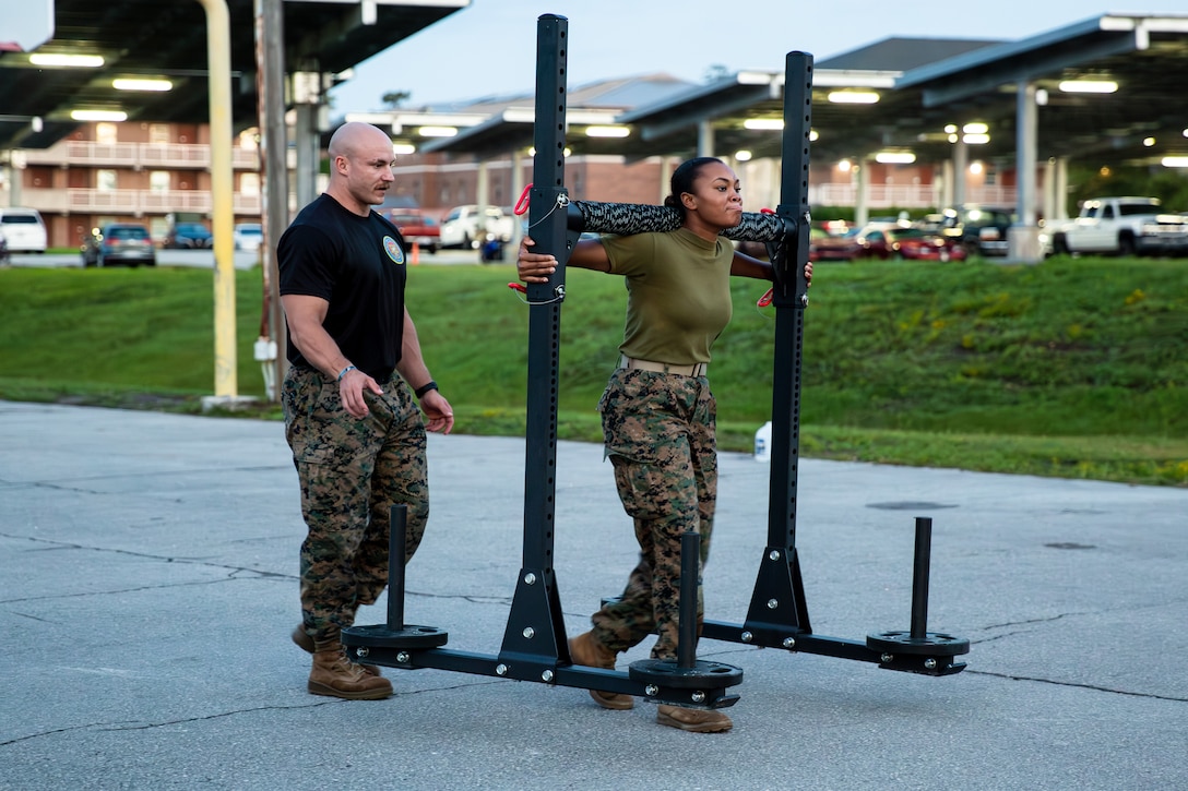 U.S. Marine Corps Staff Sgt. Geoff Laney, left, an instructor with Marine Corps Engineer School, Training Command, Marine Corps Base (MCB) Camp Lejeune, instructs a student during unit physical training on MCB Camp Lejeune, North Carolina, Aug. 20, 2024. Laney, North Carolina's Strongest Man, has claimed victory in seven Strongman competitions, set seven world records, and competed at regional, state, and national levels across the U.S. and in Okinawa, Japan, all while passionately advocating for Marines to take an active role in their personal physical training. (U.S. Marine Corps photo by Cpl. Daniela Chicas Torres)