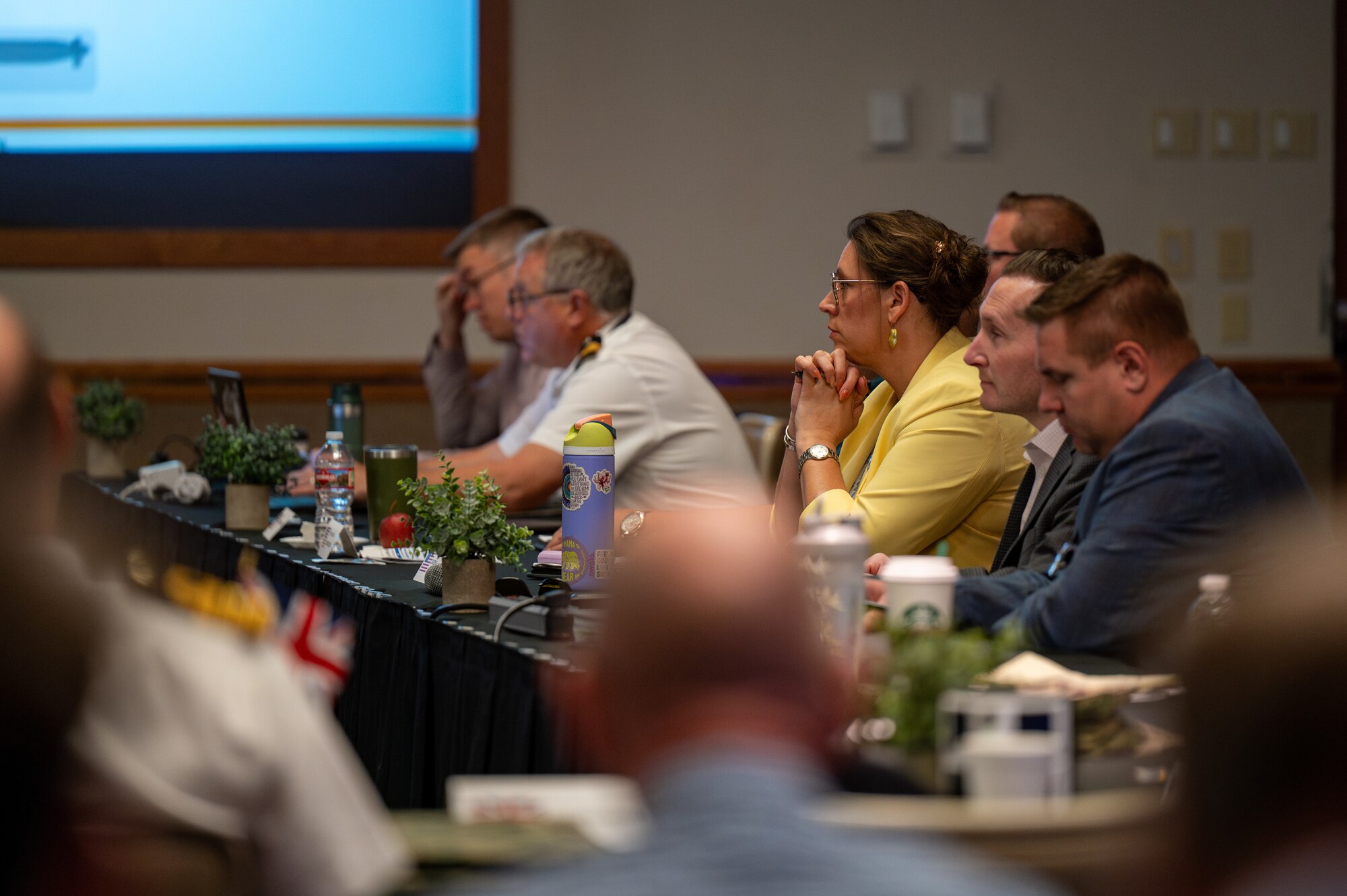 A group of panelists sit at a table during a presentation.