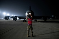 U.S. Air Force Staff Sgt. Jesse Lookingglass, crew chief and mechanic with the 213th Maintenance Squadron, D.C. Air National Guard, guides a KC-135 into a parking spot on Al Udeid Air Base, Qatar, Aug. 1, 2022. After landing, the aircraft taxis to the ramp, where any required maintenance is performed. Staff Sgt. Lookingglass was an Airmen maintainer with the 379th Expeditionary Aircraft Maintenance Squadron during that time.