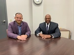 Two men sitting at a table, smiling.