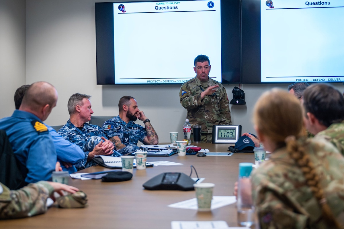 Military members engage in discussion around a conference table.
