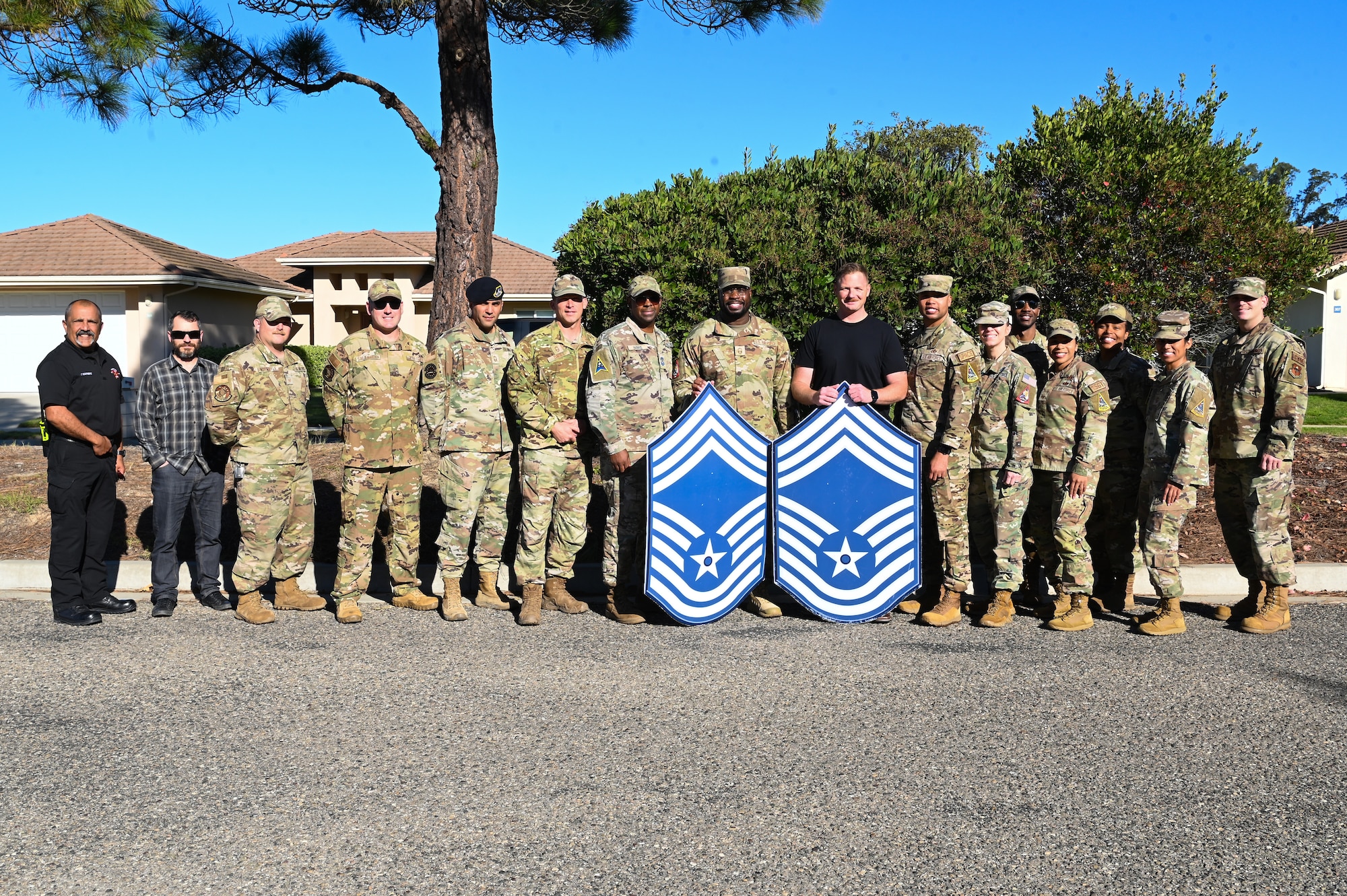 vandenberg chiefs pose with chief master sgt selects with chief master sgt poster boards, bottle of wine, and plaque