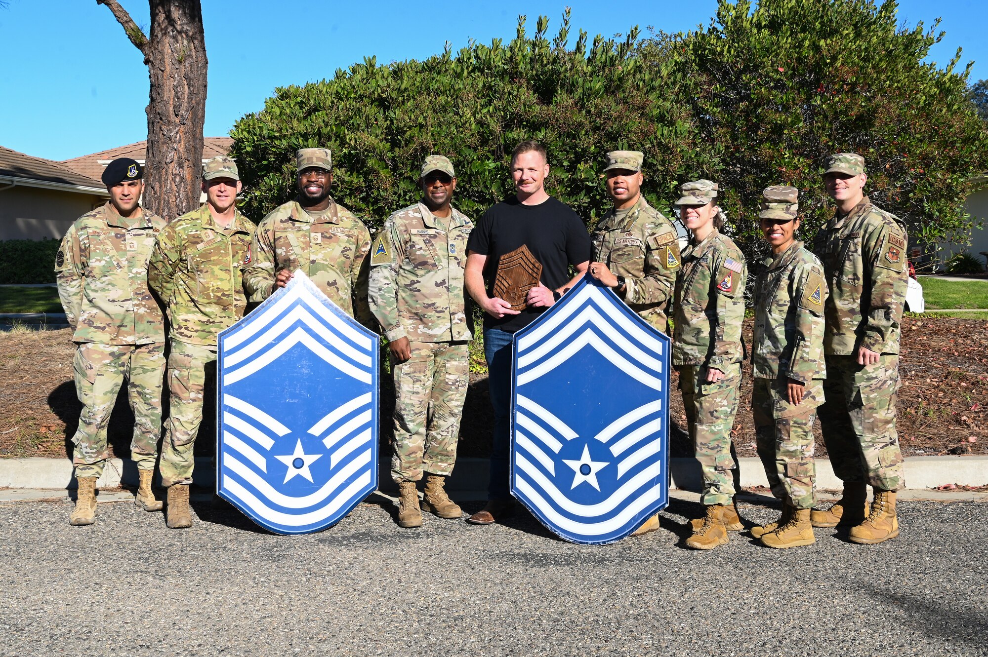 vandenberg chiefs pose with chief master sgt selects with chief master sgt poster boards, bottle of wine, and plaque