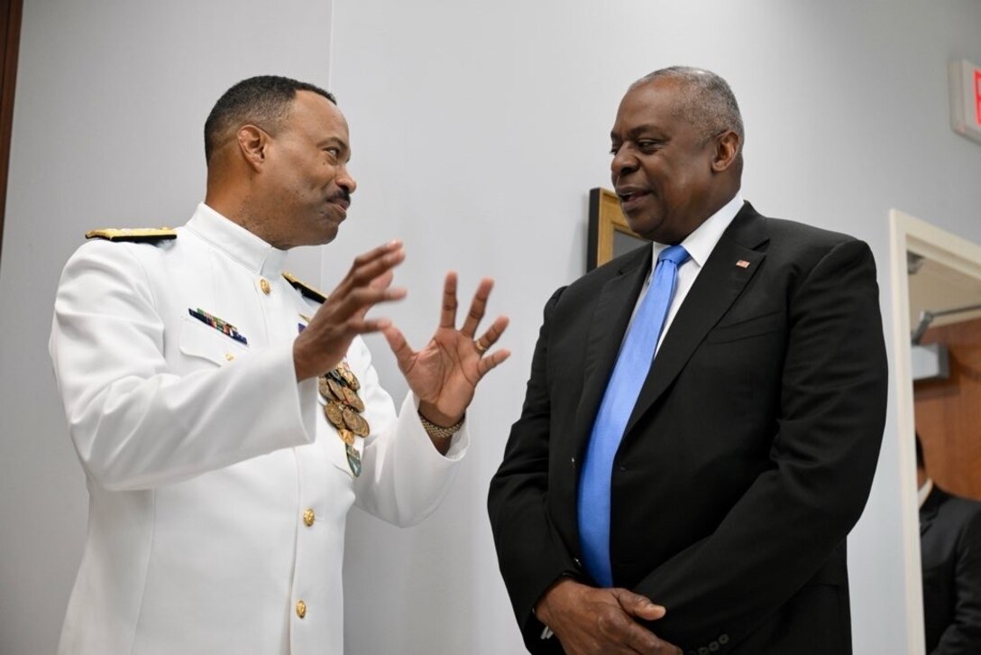A government official in business attire meets with a high-ranking navy officer.