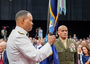 A man in a white uniform holds a flag.