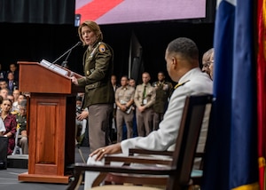 A woman in military uniform speaks from a podium.