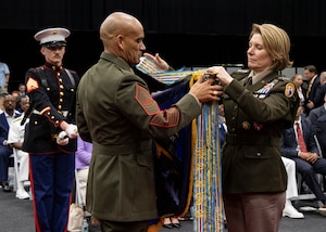 Military personnel in uniform hold a flag.