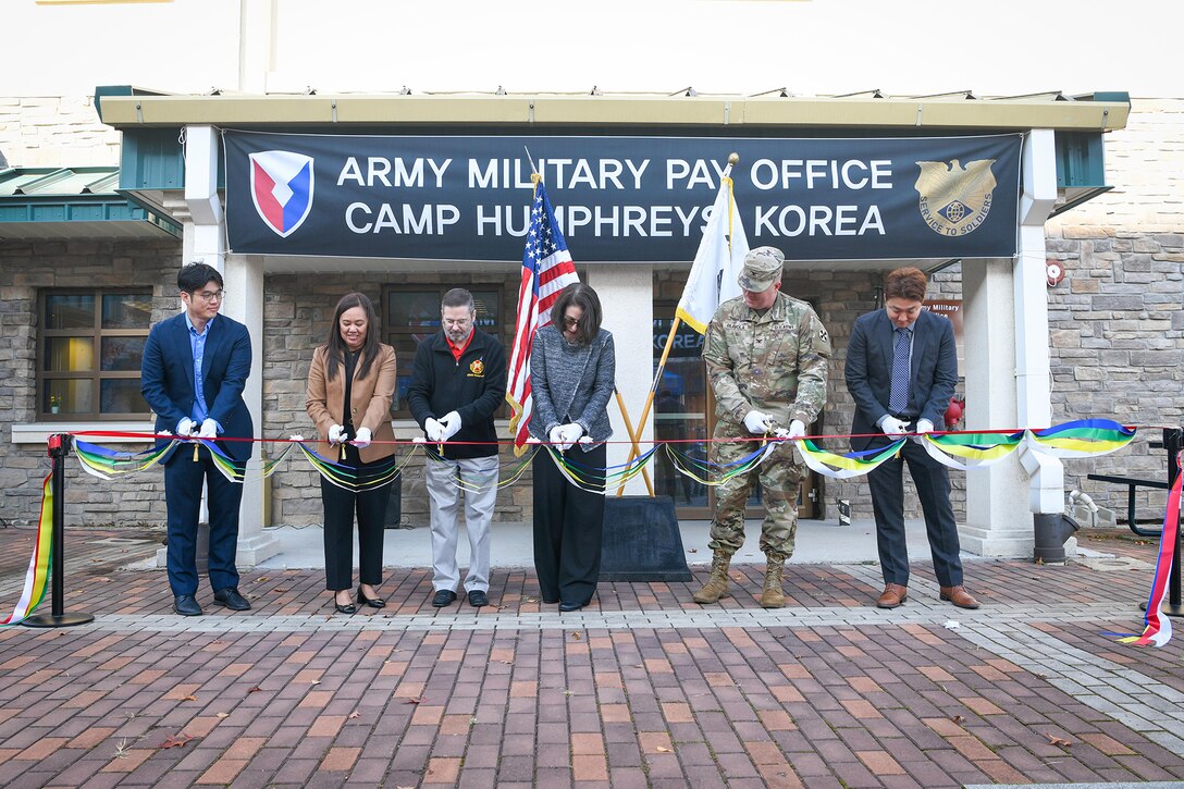 From left to right: Ki Sang Yi, Army Military Pay Office Korea Debt Management and Reserve Pay Section lead; Patty White; Patty White, AMPO Korea director; Daniel M. Hancock, U.S. Army Garrison Humphreys deputy to the commander; Mary Jelev, U.S. Army Financial Management Command Military Pay Operations director; Col. Nicholas Paavola, Eighth Army assistant chief of staff (G8); and Hyuk Mun, AMPO Korea deputy director, cut a ribbon at a special ceremony opening AMPO Korea at Camp Humphreys, South Korea, Oct. 31, 2024. USAFMCOM opened the new AMPO on Camp Humphreys as well as two satellite locations at Camps Walker and Casey. (U.S. Army photo by Cpl. Kianna Scott)