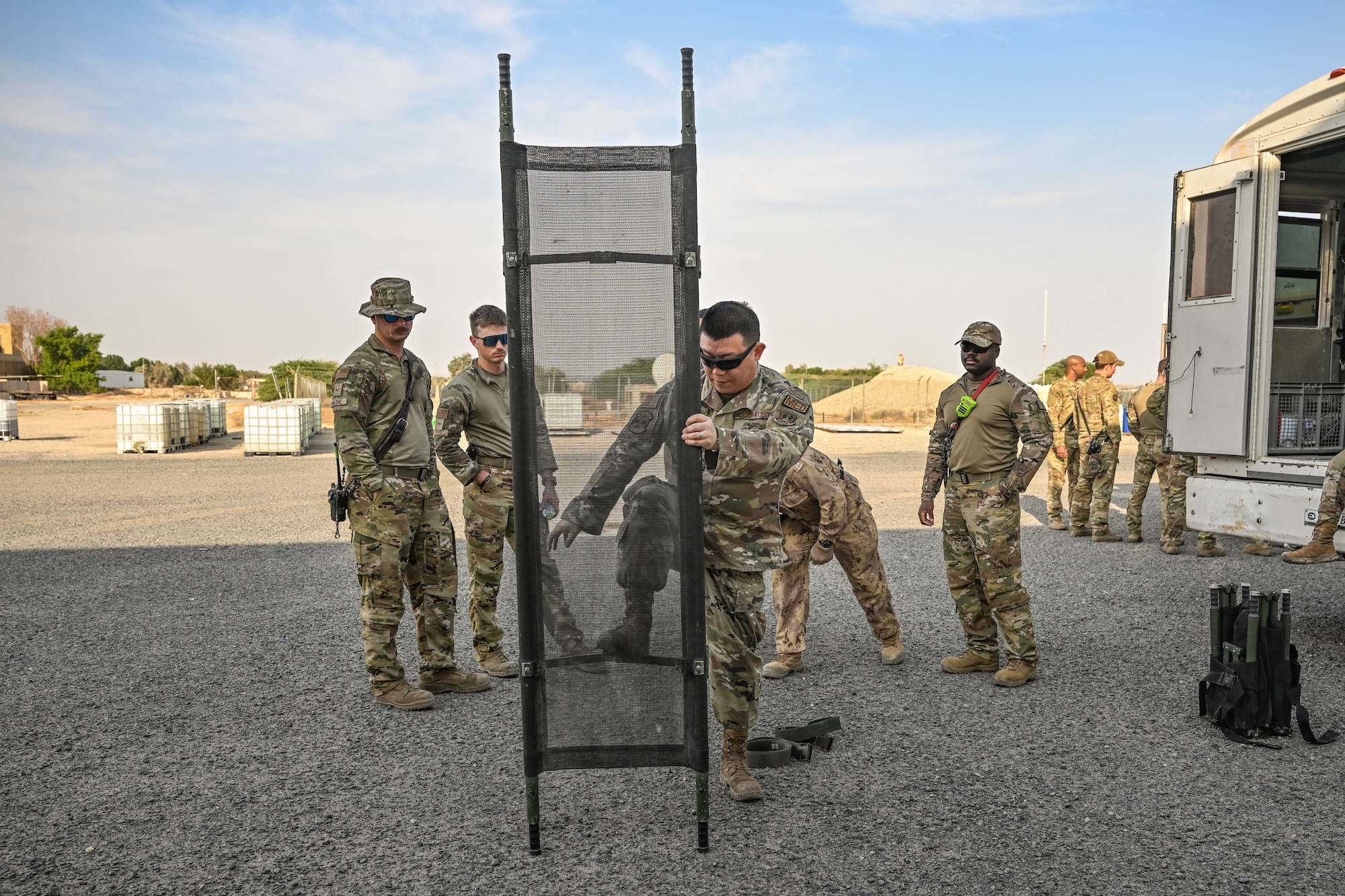 A man in uniform opens a litter in front of other men in uniform.