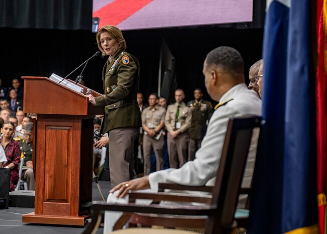 A woman in military uniform speaks from a podium.