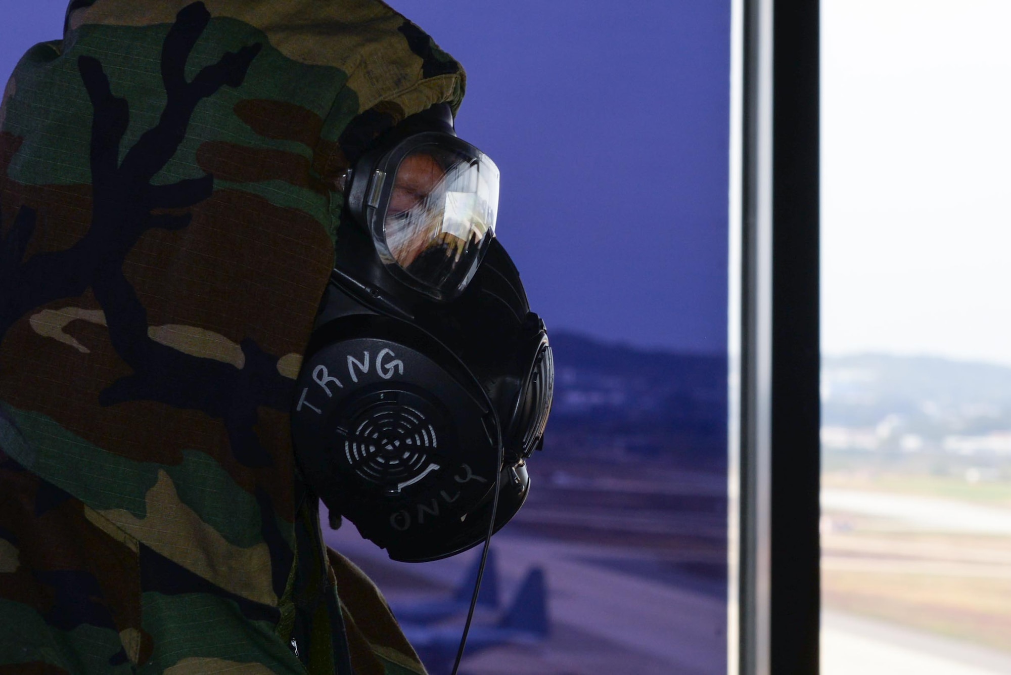 U.S. Air Force Capt. Kate Evans, 51st Operations Support Squadron air traffic controller, watches her team conduct live air traffic operations in M-50 gas masks during Beverly Herd 25-1 at Osan Air Base, Republic of Korea, Oct. 29, 2024. Training is conducted throughout the year to generate combat airpower at a moment’s notice, affirming the commitment to the ROK remains ironclad and ensures regional stability throughout the U.S. Indo-Pacific theater. (U.S. Air Force photo by Staff Sgt. Kahdija Slaughter)