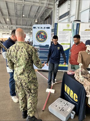 SAN DIEGO (Nov 7, 2024) NHRC's Cmdr. Ryan Smith engages with STEM students as they take part in interactive activities such as a Y-balance test, which helps scientist determine if a subject has mobility or stability issues, or problems with muscle strength deficits. NHRC supports military mission readiness with research and development that delivers high-value, high-impact solutions to the health and readiness challenges our military population faces on the battlefield, at sea, on foreign shores and at home. (U.S. Navy photo by John Marciano/released)