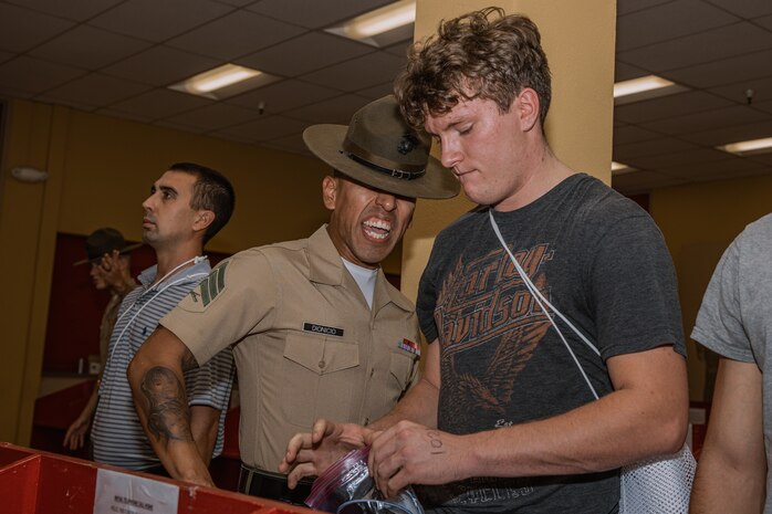 U.S. Marine Corps Sgt. Luis Dionicio, a drill instructor with Receiving Company, Support Battalion, instructs a recruit during the Bravo Company, 1st Recruit Training Battalion, receiving event at Marine Corps Recruit Depot San Diego, California, Oct. 28, 2024. During the receiving process, recruits are taken to the United States Organizations for accountability, checked for contraband, given haircuts, make scripted phone calls home, and issued gear required for training. (U.S. Marine Corps photo by Cpl. Sarah M. Grawcock)