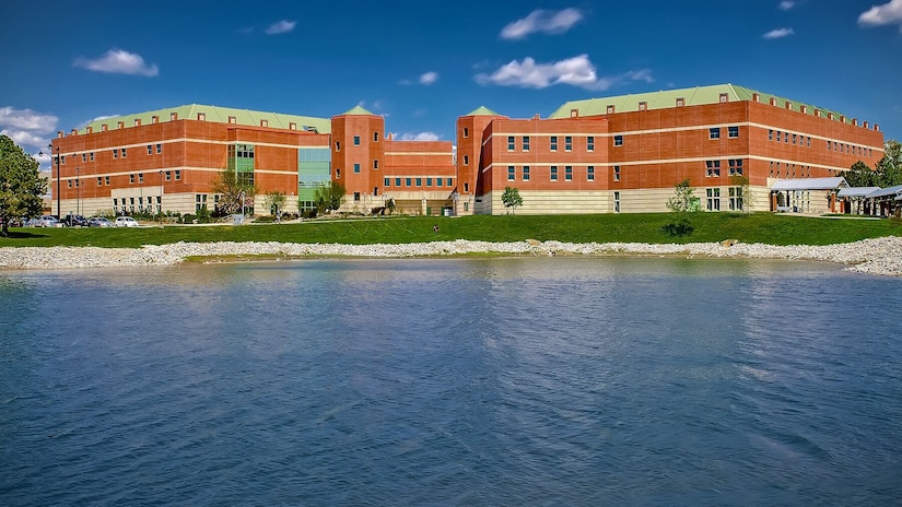 A large building is photographed with a lake in the foreground.