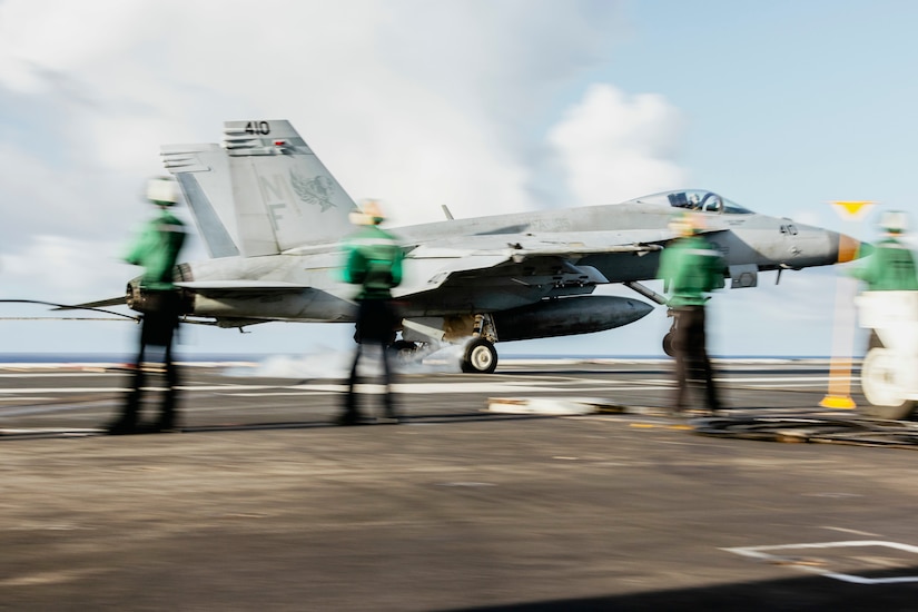 A large jet lands on the deck of a ship.