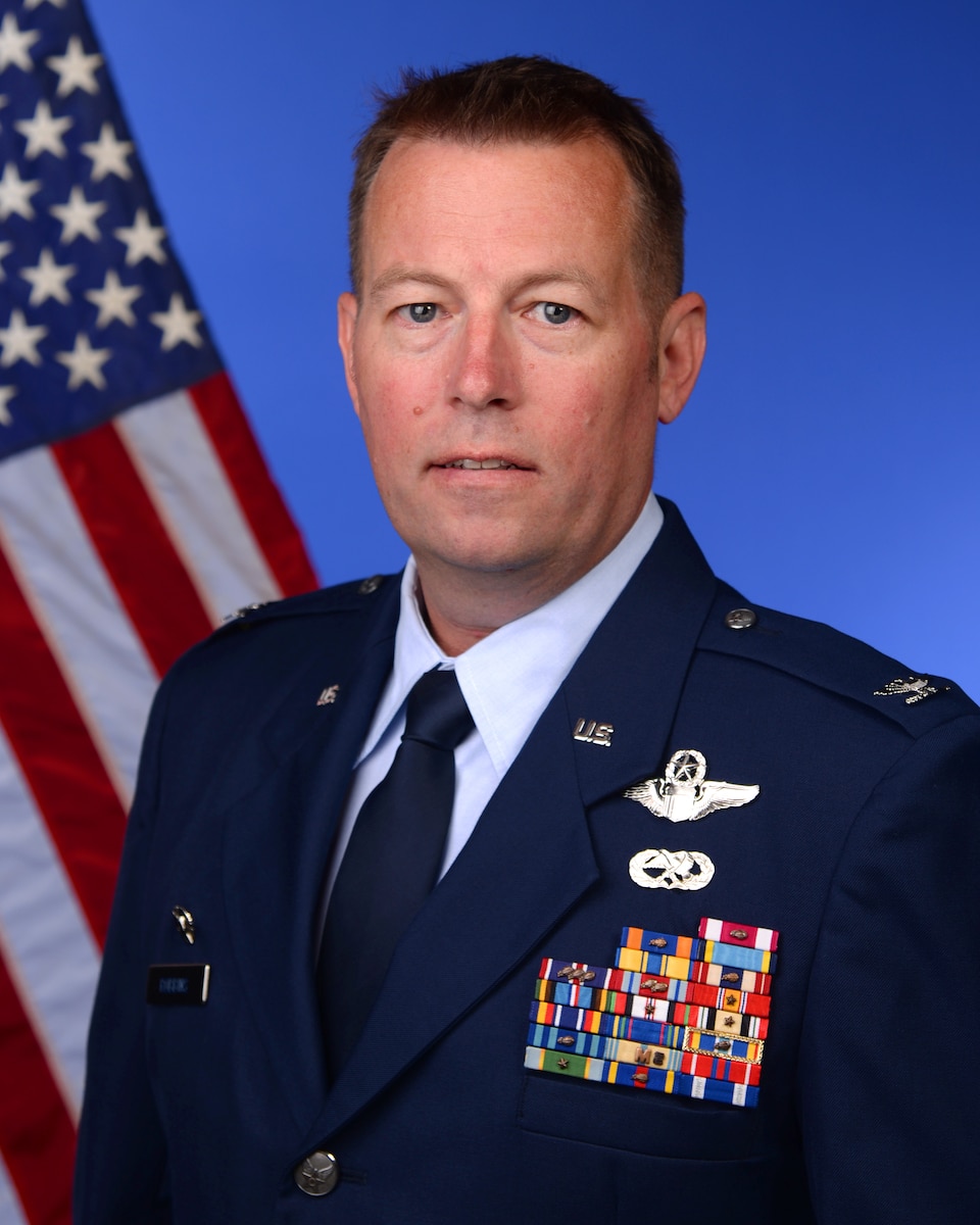 Col. Benjamin Robbins poses for an official photo in front of a blue background and an American Flag.