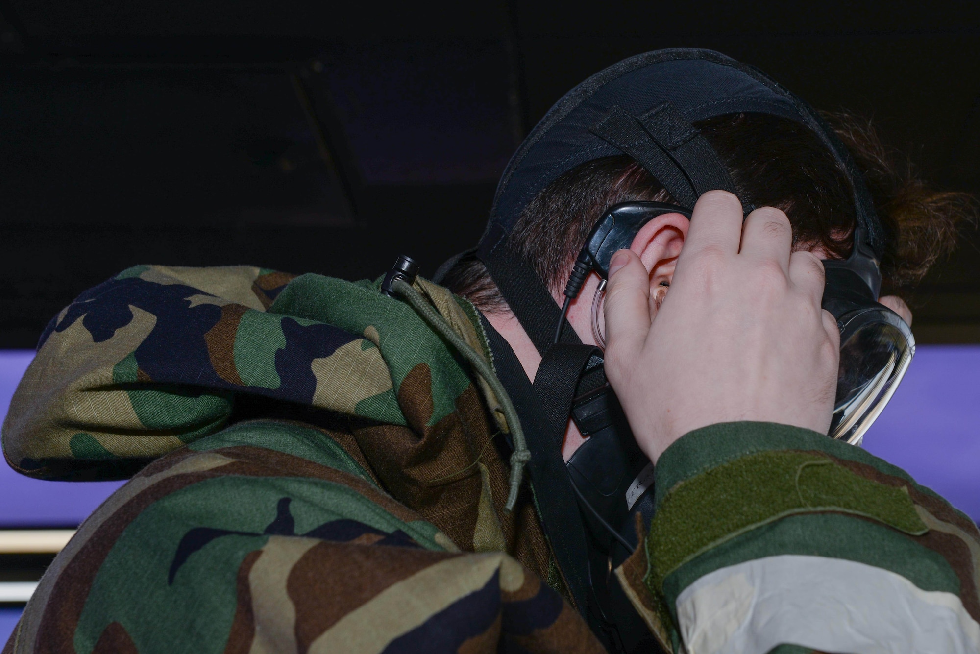 U.S. Air Force Senior Airman Connor Butler, 51st Operations Support Squadron air traffic controller, dons an earpiece under his mission oriented protective posture gear during Beverly Herd 25-1 at Osan Air Base, Republic of Korea, Oct. 29, 2024. The 51st OSS is working with the University of Oklahoma and the Air Force Flight Standards Agency to test, evaluate and create a high-tech transmitter to generate effective air-to-ground and ground-to-air communications for air traffic controllers. (U.S. Air Force photo by Staff Sgt. Kahdija Slaughter)