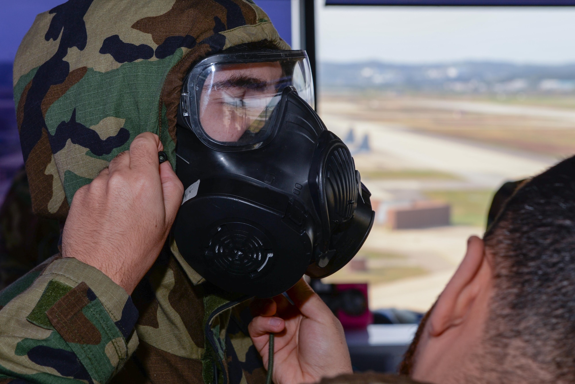 U.S. Air Force Senior Airman Connor Butler, 51st Operations Support Squadron air traffic controller, receives help while donning mission oriented protective posture gear during Beverly Herd 25-1 at Osan Air Base, Republic of Korea, Oct. 29, 2024. Beverly Herd provides the 51st Fighter Wing the opportunity to practice their skills in simulated contingency scenarios. (U.S. Air Force photo by Staff Sgt. Kahdija Slaughter)