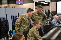uniformed military members flying flight simulators