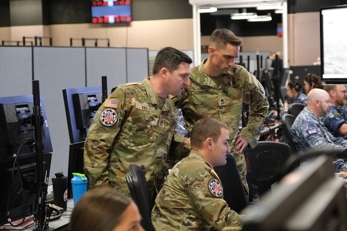 uniformed military members flying flight simulators